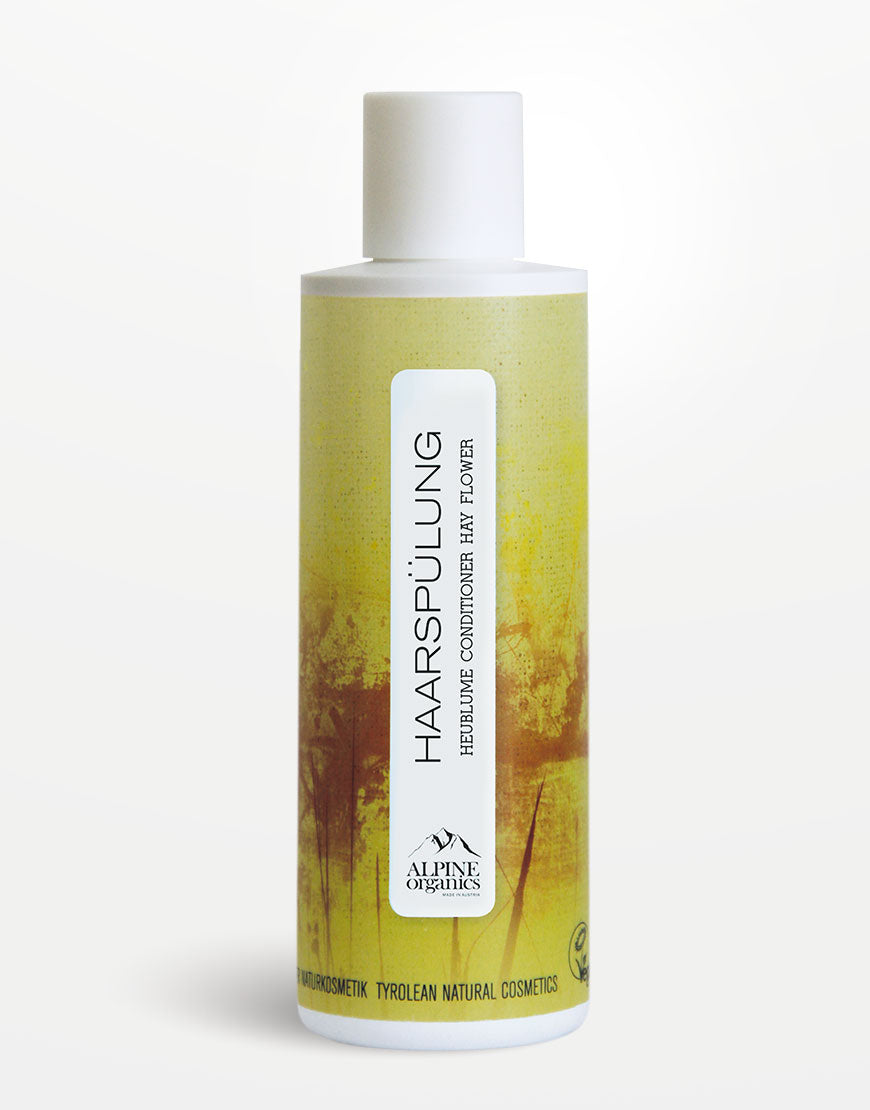 Haarspülung mit Heublume & Haselnussöl für glänzende & geschmeidige Haare. Zylindrische Flasche, Alpine Organics, gelb-grünes Design mit stilisierten Gräsern, weißer Deckel.