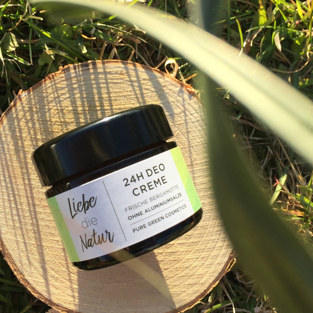 Deocreme mit Zink & Sheabutter für langanhaltenden Schutz & zarte Achselhaut | Bio & Vegan in dunklem Glas auf Holzscheibe im Gras.