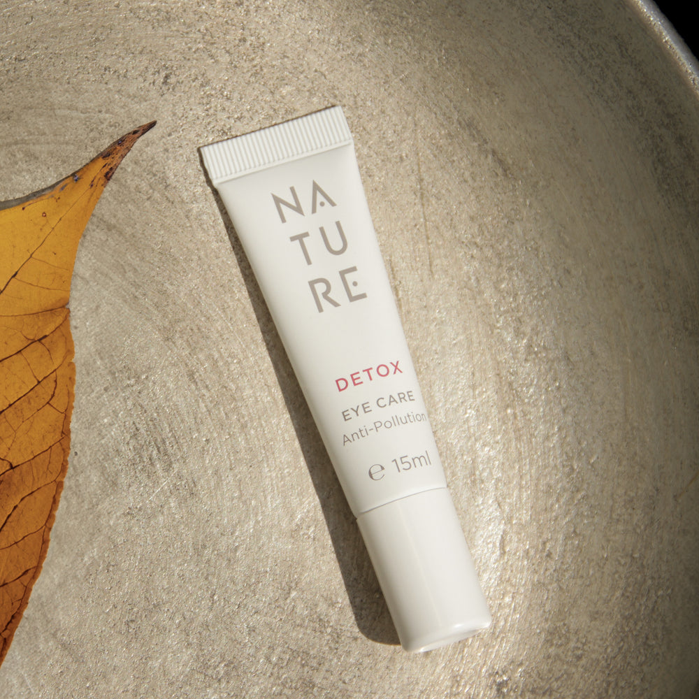 Detox-Augencreme mit Edelweiß- und Schisandra-Extrakt, 15 ml Tube, schützt vor Umwelteinflüssen, mildert Trockenheitsfältchen, auf strukturiertem Untergrund neben einem getrockneten Blatt.
