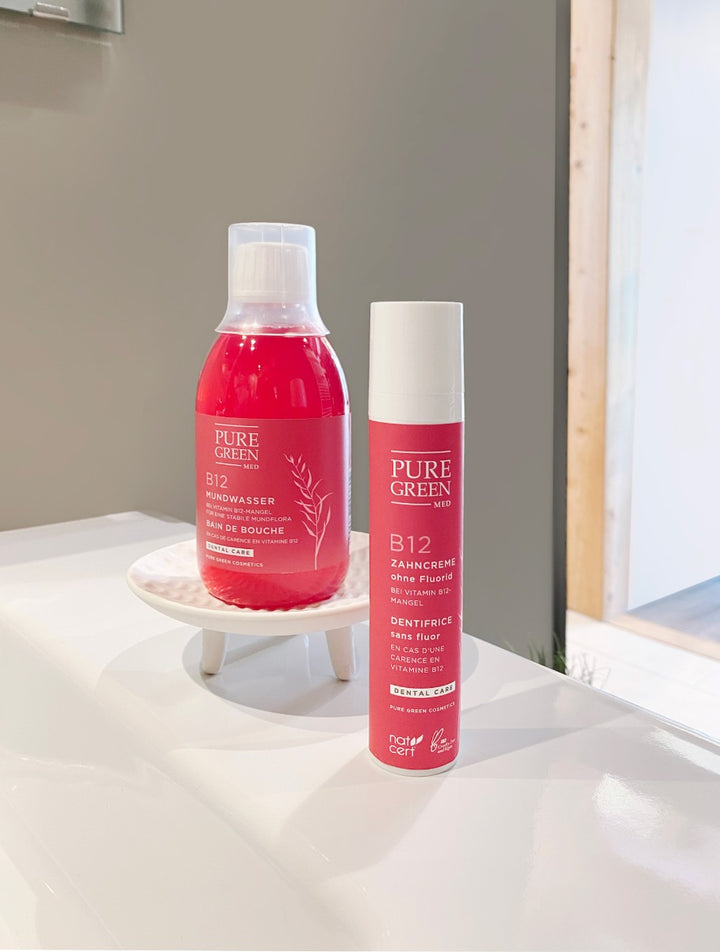 Fluoridfreie Zahncreme mit Vitamin B12 & Minzöl für gesunde Zähne & frischen Atem, neben B12 Mundwasser, auf weißer Badezimmeroberfläche.
