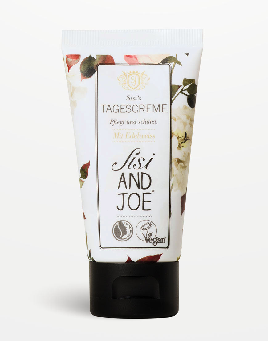 Sisi’s Tagescreme in Tube mit floralem Design, veganem Logo und schwarzem Deckel. Pflegt mit Edelweißextrakt und Traubenkernöl für harmonisierte, strahlende Haut.
