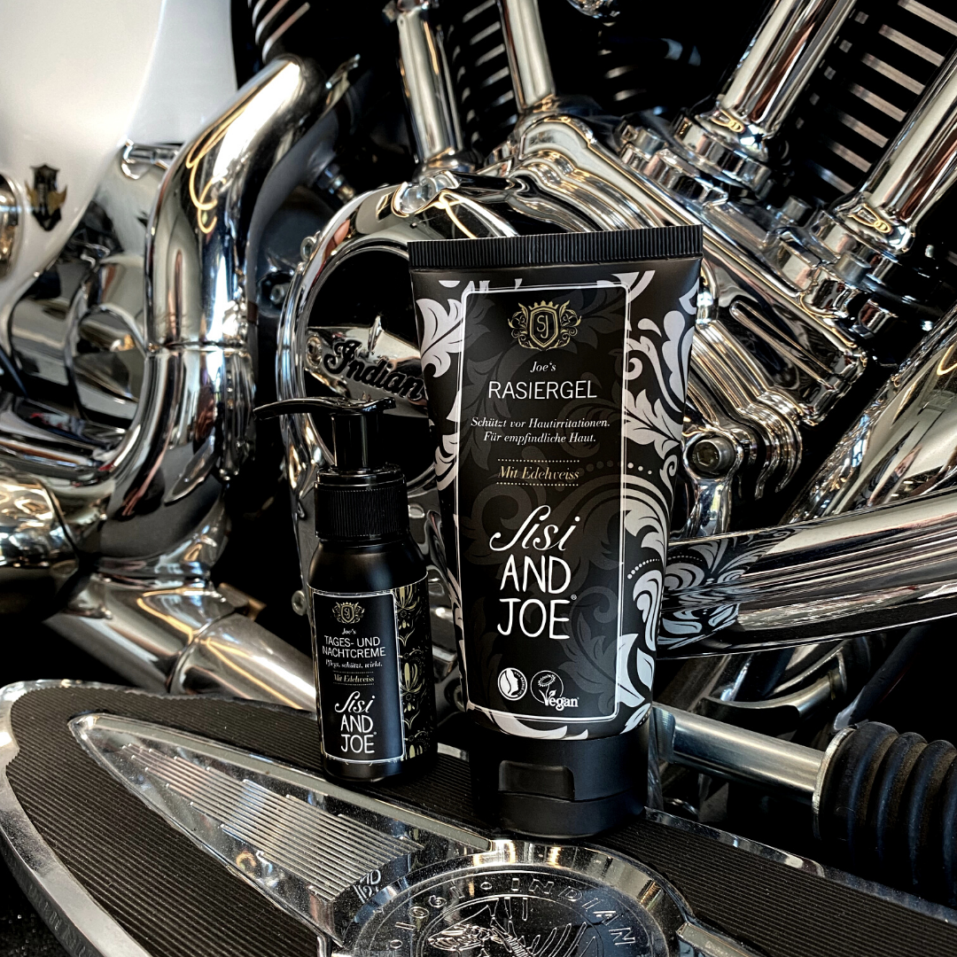 Nahaufnahme eines Motorradmotors mit zwei Behältern auf der Fußraste: Sisi and Joe veganes Rasiergel mit Kamille und Edelweißextrakt und Tages- und Nachtcreme, beide vegan.