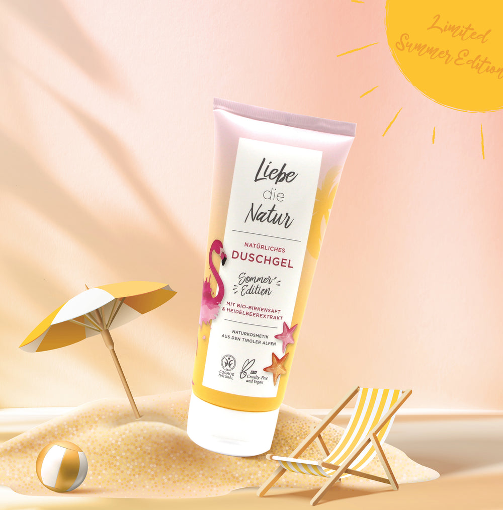 Duschgel mit Birkensaft und Heidelbeerextrakt in Strandkulisse, umgeben von Sonnenschirm, Liegestuhl und Ball. Zertifiziert Bio, vegan, sommerlich-fruchtiger Duft.
