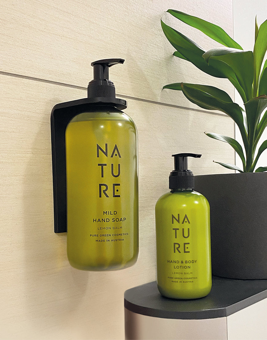 Zwei grüne Pumpflaschen von NATURE auf Regal; links ein Wandhalter aus schwarzem Acrylglas matt für 500 ml Flaschen, mit Seife, rechts Lotion-Flasche.