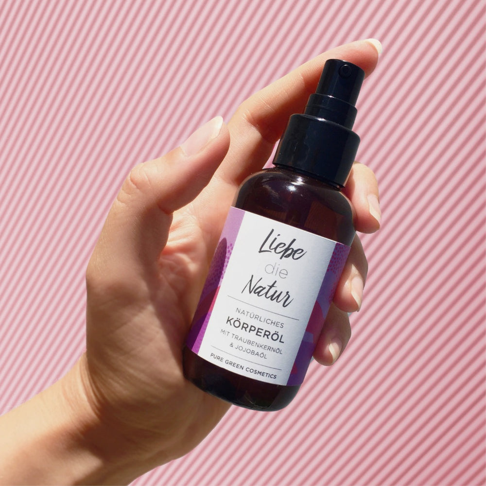 Hand hält braune Sprühflasche Körperöl mit hochwertigem Traubenkern & Jojobaöl von Pure Green Cosmetics, bietet intensive Feuchtigkeit; Bio, vegan.