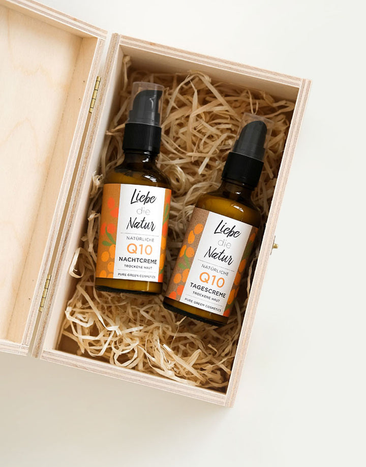 Q10 Anti-Aging Gesichtspflege-Set in Holzbox: Zwei amberfarbene Pumpflaschen mit Tages- und Nachtcreme, vegan und bio, für straffere Haut und intensive Feuchtigkeit.