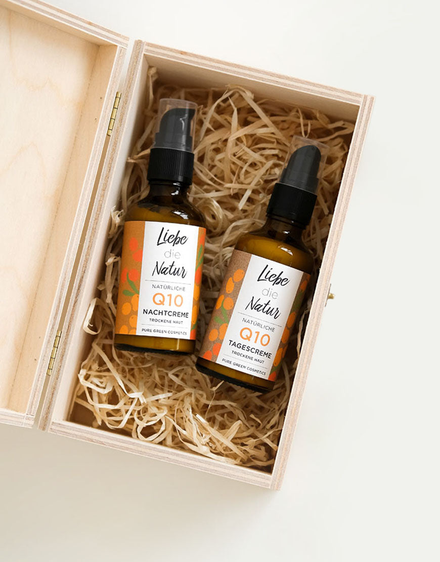 Q10 Anti-Aging Gesichtspflege-Set in Holzbox: Zwei amberfarbene Pumpflaschen mit Tages- und Nachtcreme, vegan und bio, für straffere Haut und intensive Feuchtigkeit.