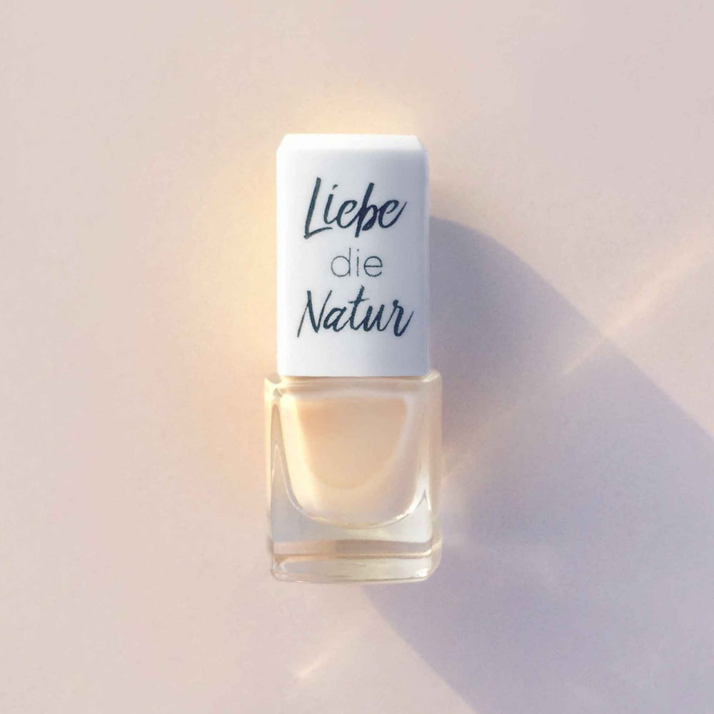 Nagellack in einem quadratischen Glasfläschchen mit weißem Deckel, beschriftet mit „Liebe die Natur“, wasserbasierte Formel, natürliche Farbpigmente, bio und vegan.