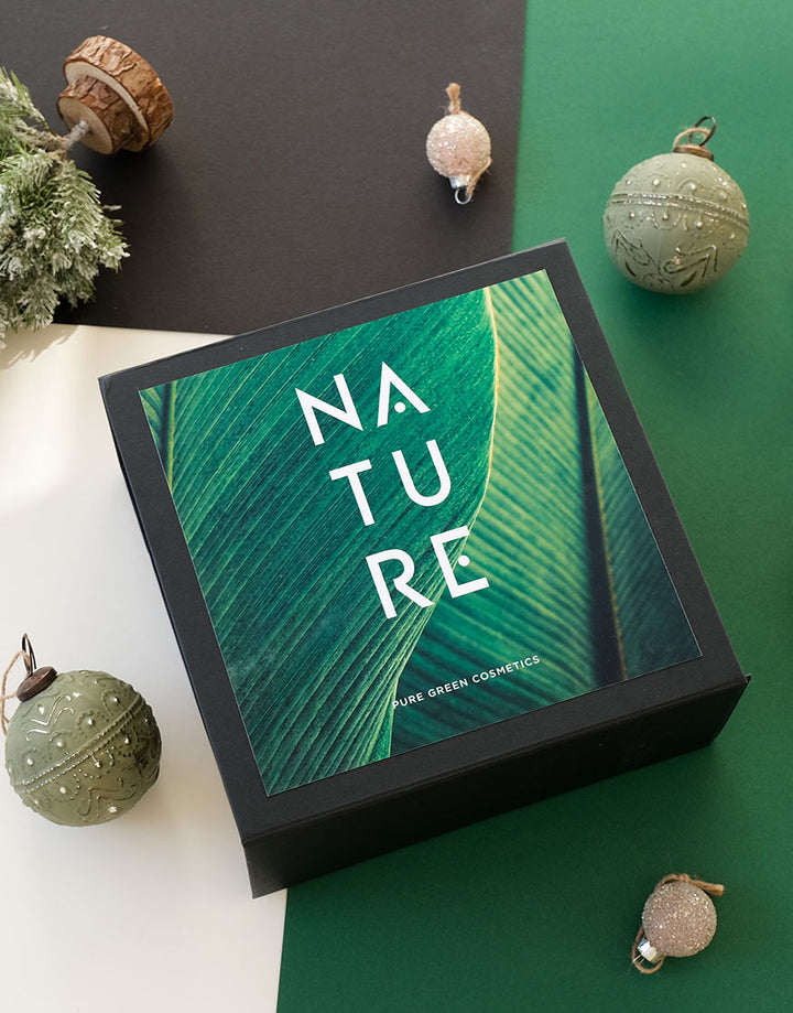 Geschenkset mit Bodylotion & Duschgel für gepflegte Haut in einer mattschwarzen Box mit Blattdruck, umgeben von festlichen Dekorationen. Enthält reichhaltige, vegane Naturkosmetik.