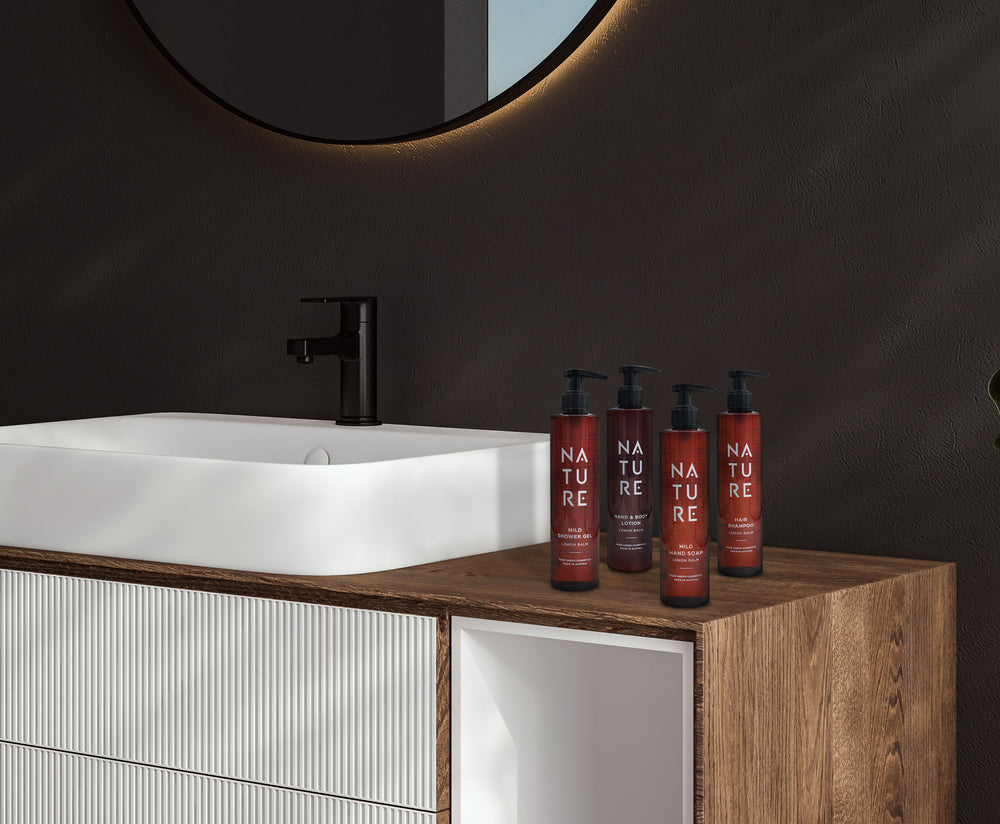 Moderne Badezimmer-Einrichtung mit weißem Aufsatzwaschbecken und schwarzen Armaturen. Rechts stehen vier rote NATURE-Pumpflaschen, darunter Bodylotion mit Aprikosenextrakt für gepflegte Haut.
