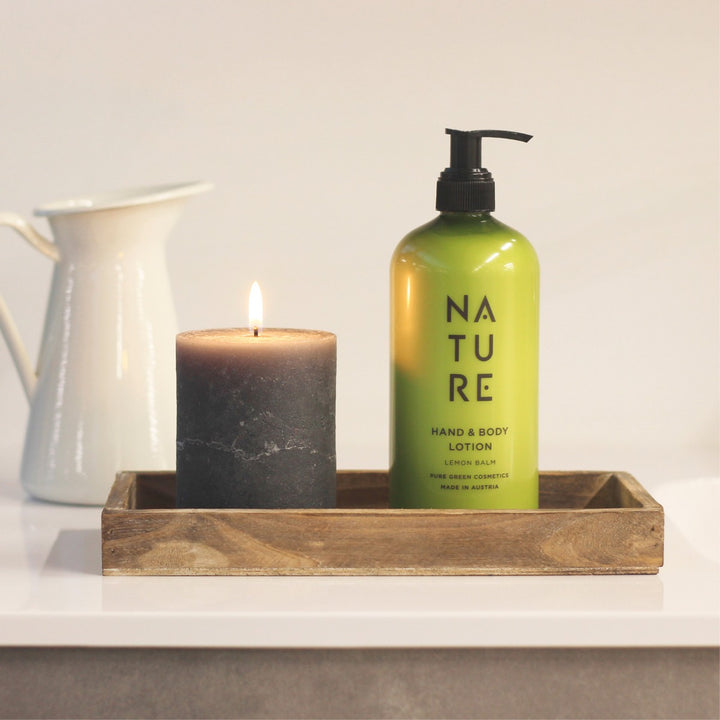 Hand- & Bodylotion mit Aprikosenkernöl & Vitamin E auf Holztablett neben schwarzer Kerze, ideal für seidig-weiche, gepflegte Haut. Bio, vegan, schnell einziehend.