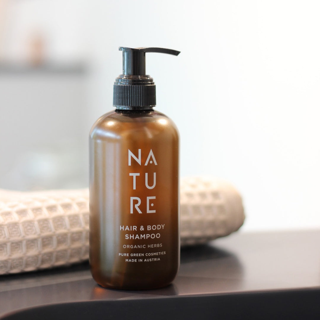 NATURE Hair-&-Body-Shampoo mit Apfelsaft und pflanzlichem Glycerin, in einer Bernsteinpumpe, bietet sanfte Reinigung und seidiges Haar, umgeben von Bio-Kräuterduft.